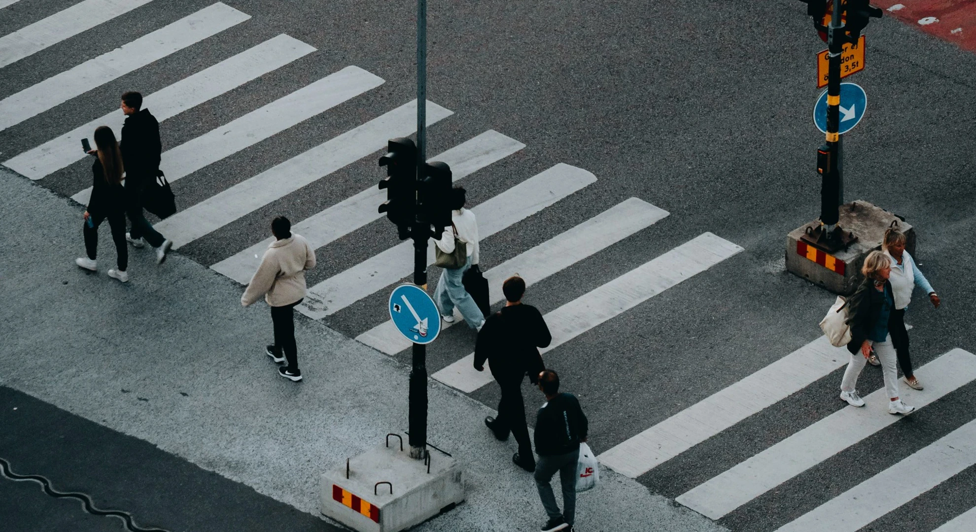 Zebrastreifen in Stockholm, auf dem Menschen aus der Vogelperspektive zu Fuß die Straße überqueren